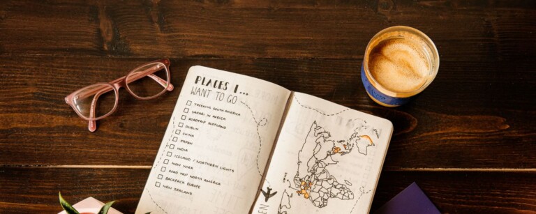 book on table with trip planning details written with a coffee by side