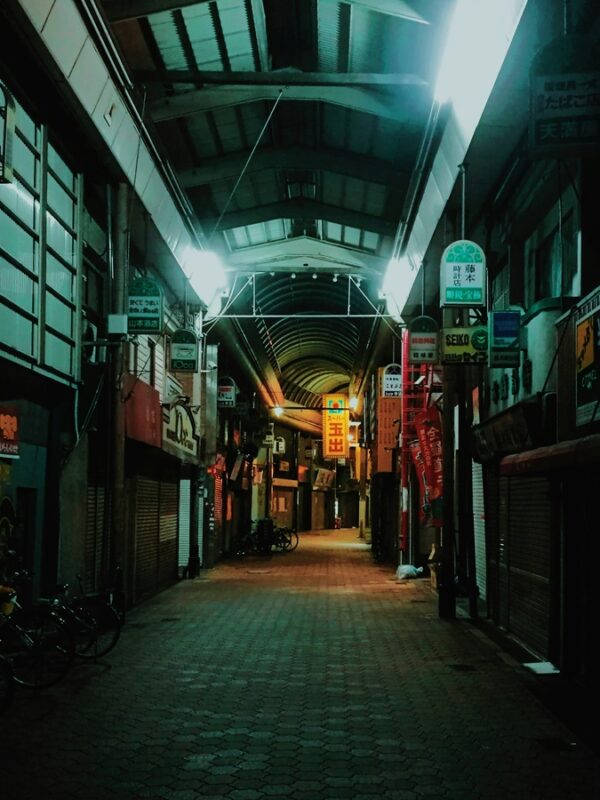 Quiet night view of an empty shopping arcade in Osaka, featuring closed storefronts and a peaceful, dimly-lit atmosphere