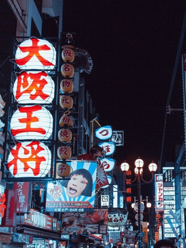 Brightly lit signs and large lanterns in Dotonbori at night, reflecting the energetic and colourful vibe of Osaka’s entertainment district.