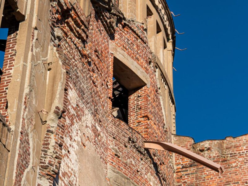 Detailed close-up of the damaged brick wall of the Atomic Bomb Dome, showing the effects of the bombing, against a clear blue sky.