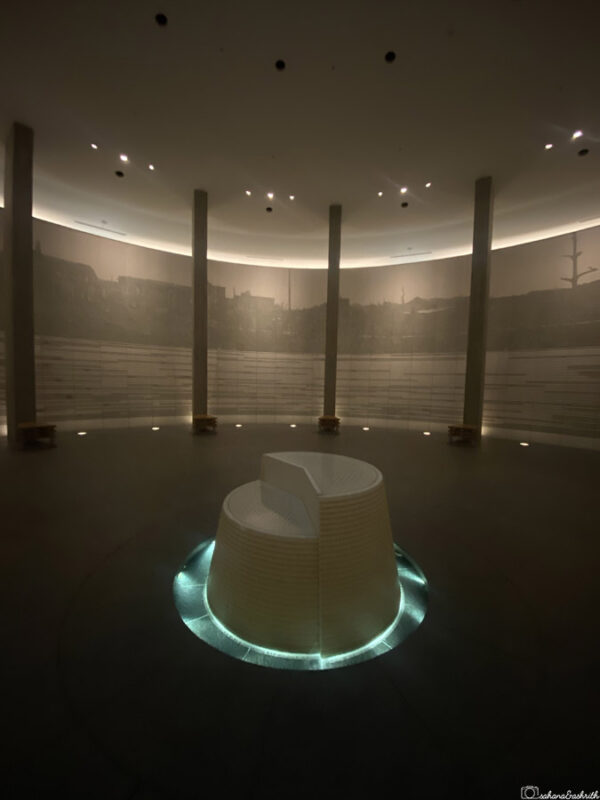 Hiroshima Peace Memorial Hall’s quiet interior with central white monument under soft lighting, representing remembrance and resilience