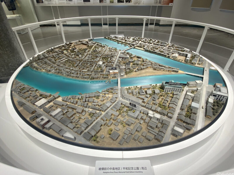 A detailed model of the Nakajima Area in Hiroshima, displayed at Hiroshima Peace Memorial Museum. The model illustrates the layout of buildings, roads, and waterways in the area before the atomic bombing, with a blue river running through the centre and densely packed structures on both sides.