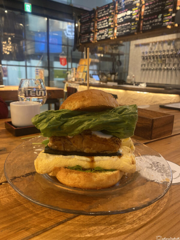 Close-up of gourmet chicken burger served in a Hiroshima café, topped with fresh lettuce, showing popular local fusion food experience