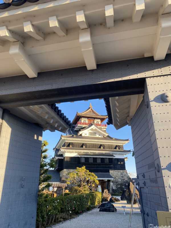 A view of Kiyosu Castle seen through the grand entrance gate, with traditional architecture and a clear blue sky
