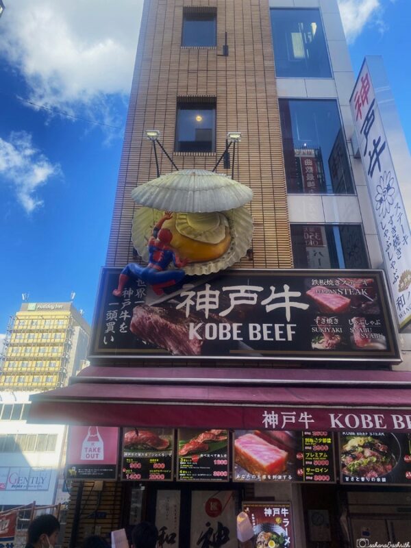 Kobe beef restaurant in Osaka with a large scallop and Spiderman figure on the sign, capturing the unique and playful advertising style in Dotonbori.