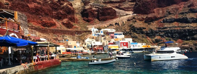 turquoise green water at the foothill of red soil mountain in oia