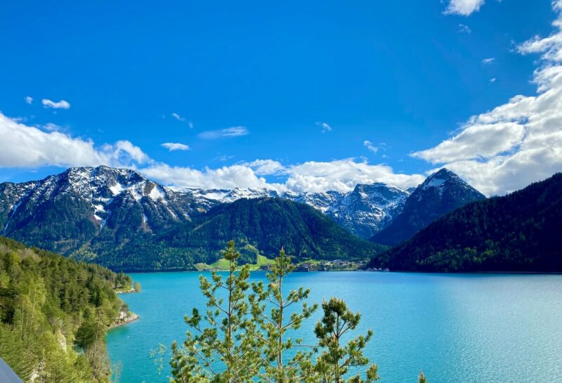 Snow-capped peaks rise above the clear blue waters of Lake Achensee in Tirol, Austria.