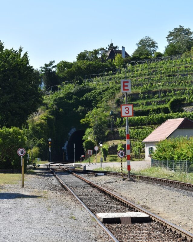 Train tracks lead to a tunnel surrounded by vineyards in Austria’s peaceful countryside.