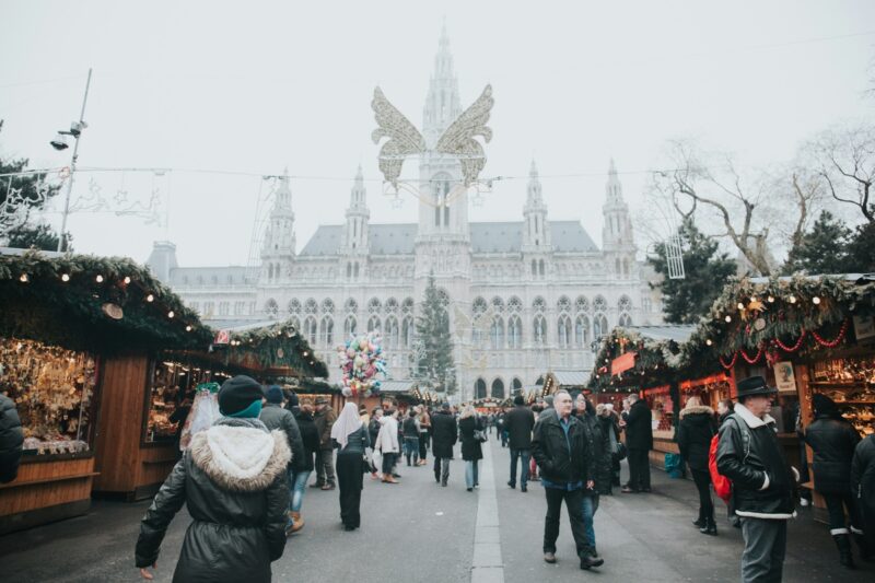 bustling Christmas market at the Vienna City Hall, with stalls selling festive goods and a crowd of people enjoying the market in the winter holiday season