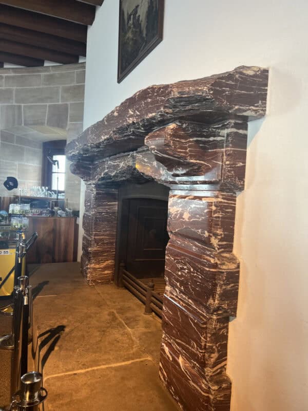 Close-up of a large red marble fireplace with angular carvings inside the Eagle’s Nest building
