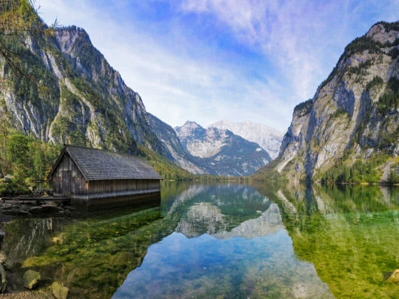 Wooden boat hut on the clear waters of Obersee with sharp mountain peaks and full reflections in the lake.