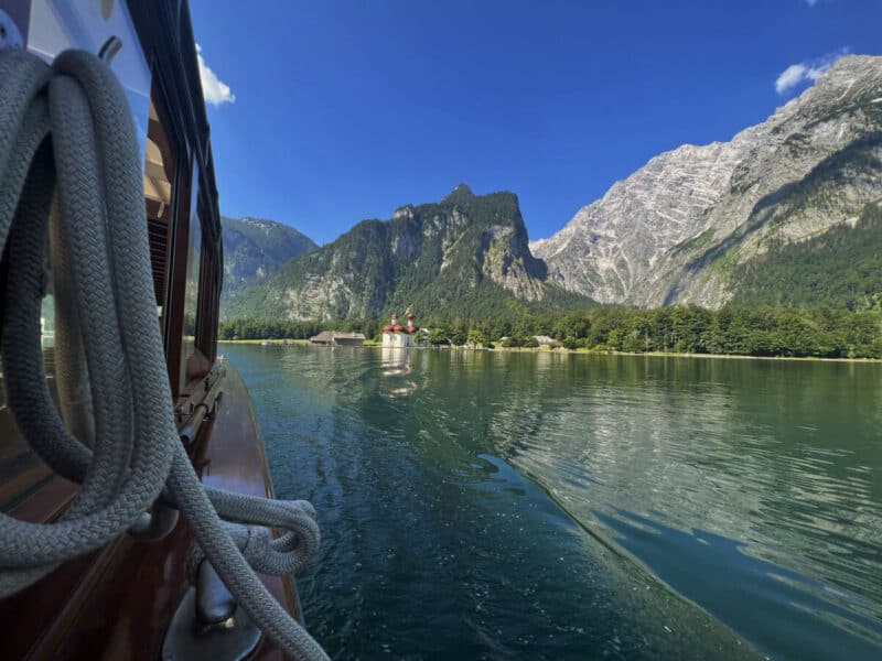View from inside the electric boat approaching St. Bartholomä, with lake reflections and alpine peaks ahead.