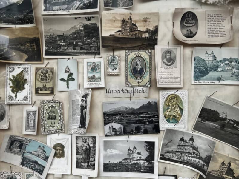 Vintage postcards, religious prints and black-and-white photos pinned together in a souvenir shop display