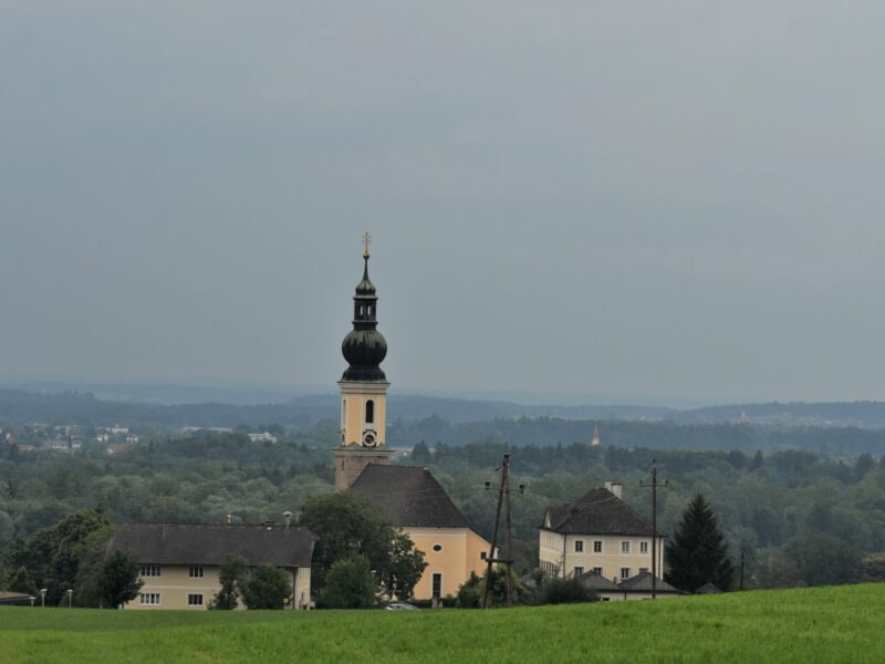 distant view of Bergheim church with onion dome tower surrounded by open fields and forest