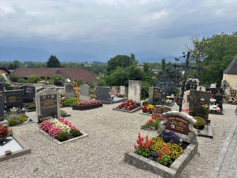 Colourful cemetery in Bergheim with flower-decked graves and views of the Alps in the background