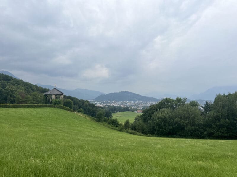 Crucifixion shrine surrounded by trimmed hedges overlooking Salzburg city and distant mountain range