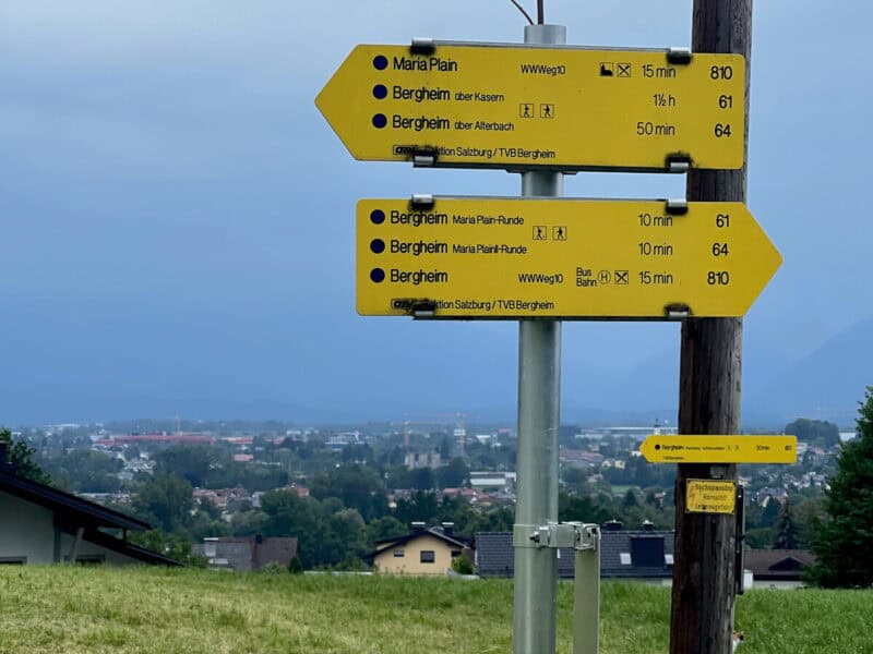 Yellow hiking trail signpost showing time-based directions to Maria Plain and Bergheim