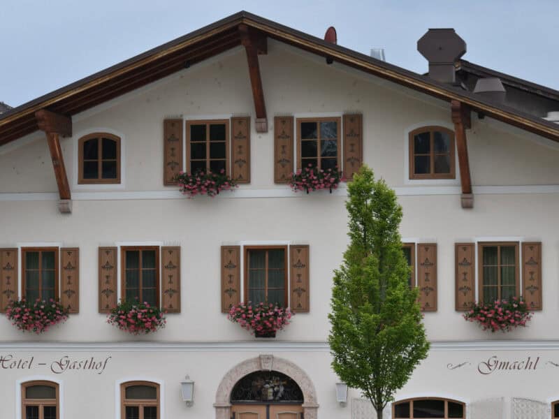 Close-up of Gasthof Gmachl hotel in Bergheim with wooden shutters and flower boxes on white walls
