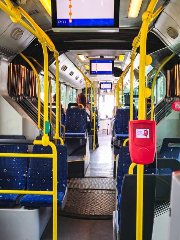 Inside a Salzburg trolleybus showing empty blue seats, yellow poles, and digital stop display screens