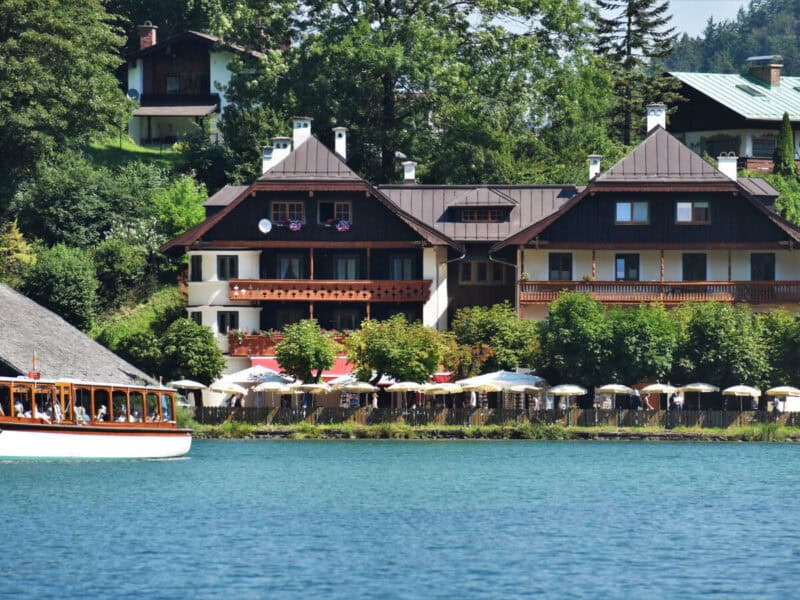Cafés and guesthouses along Königssee’s edge, with rows of sun umbrellas and boats docking nearby.