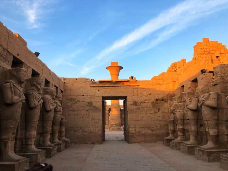 Row of statues at Karnak Temple in Luxor, Egypt, glowing in the evening light.