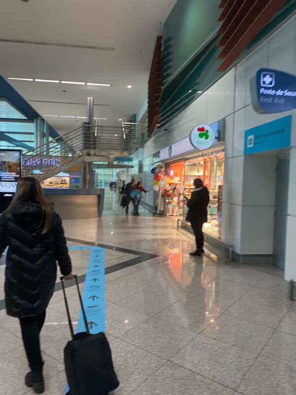 travelelrs walking inside Porto airport beside shops