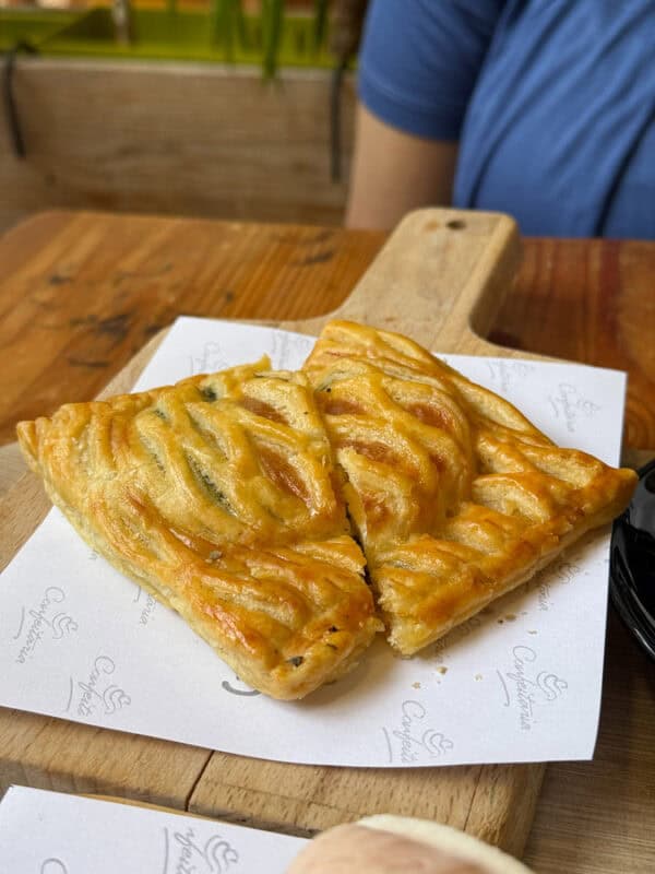 Portuguese style Golden puff pastry parcels filled with spinach and veggies, served on a wooden board at a café in funchal