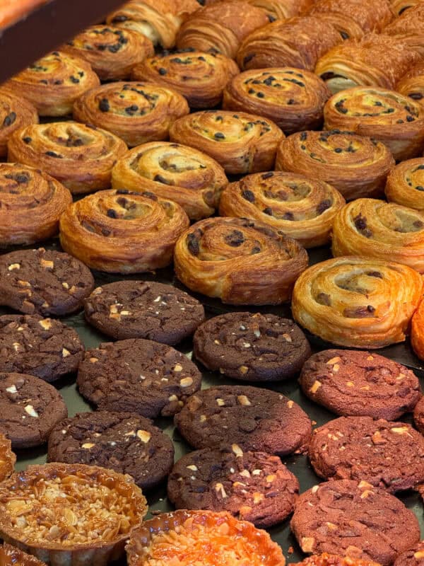 Bakery tray filled with chocolate cookies and spiral pastries with raisins at a Portuguese pastry shop.