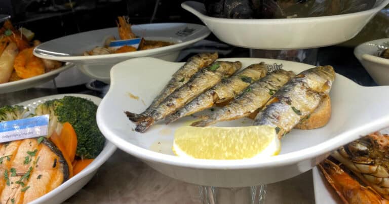 traditional portuguse grilled sardines on a plate with slice of lemon beside