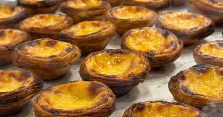 Portuguese dessert pastel de nata arranged in a glass shelf at a bakery