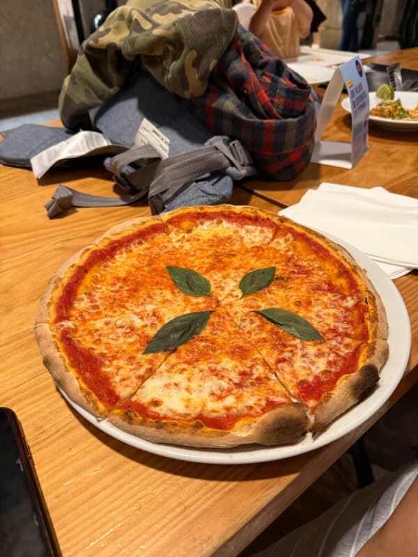 Margherita pizza with basil leaves served on a wooden table at a casual restaurant in Portugal.