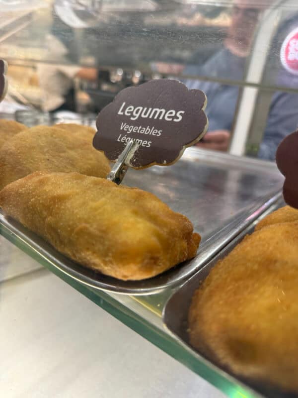 Fried vegetable pastries labelled legumes displayed in a hot food counter at a Portuguese bakery.
