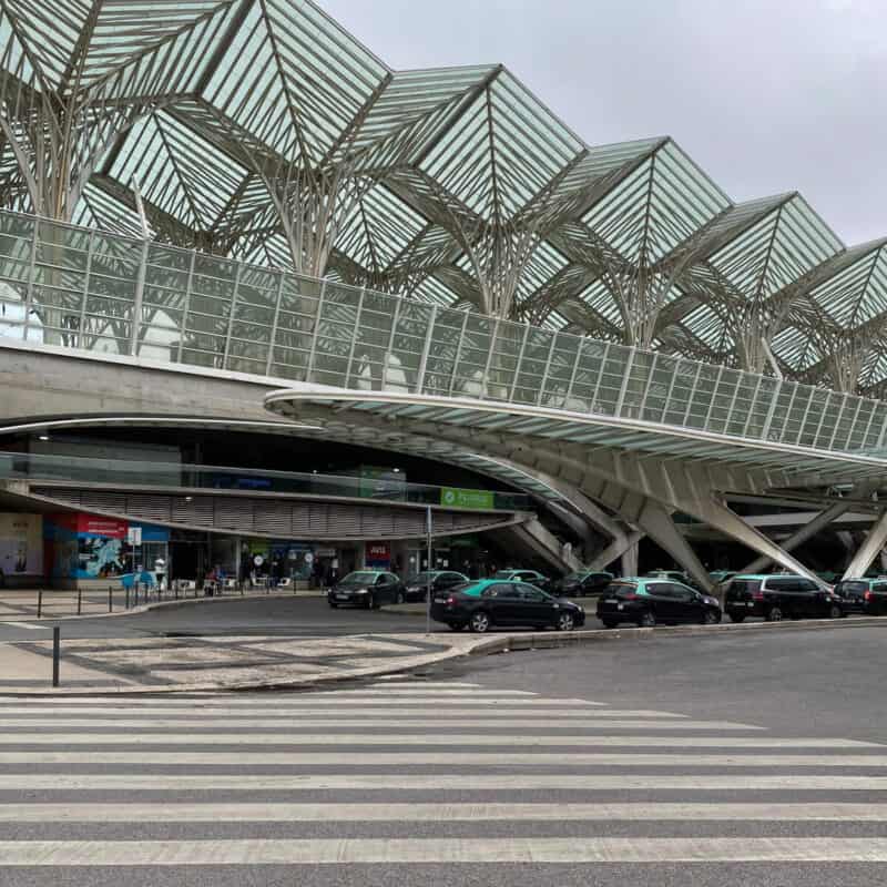 Modern building exterior of Lisbon Oriente station with glass roof and parked cars outside