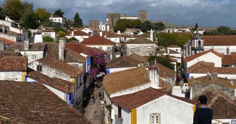 View of Óbidos Portugal with tiled rooftops and castle walls in the background