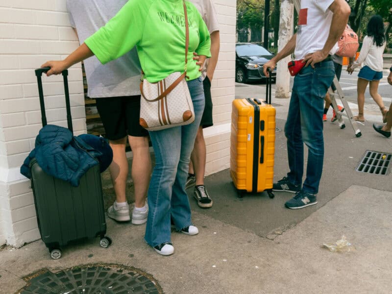 Travellers standing on a Lisbon street with suitcases waiting outside with luggage beside them
