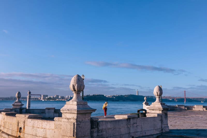 View of the Tagus River and 25 de Abril Bridge from a waterfront spot in Lisbon during blue hour