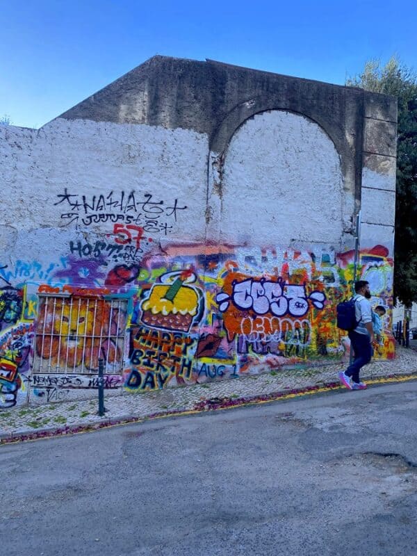 Travessa do Fala-Só in Lisbon with colourful graffiti covering a wall beside a quiet residential street