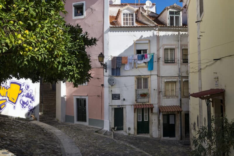 Rua de São Miguel in Alfama Lisbon with pastel houses, hanging laundry and steep cobbled lanes