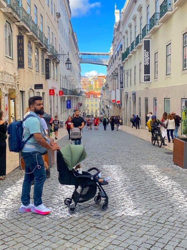 Rua Nova da Almada in Lisbon with cobbled pavements, historic buildings and a family strolling with a pram