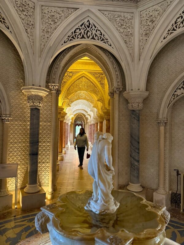 VacayWork author Sahana walking through Monserrate Palace beneath grand arches with intricate Islamic-inspired designs.