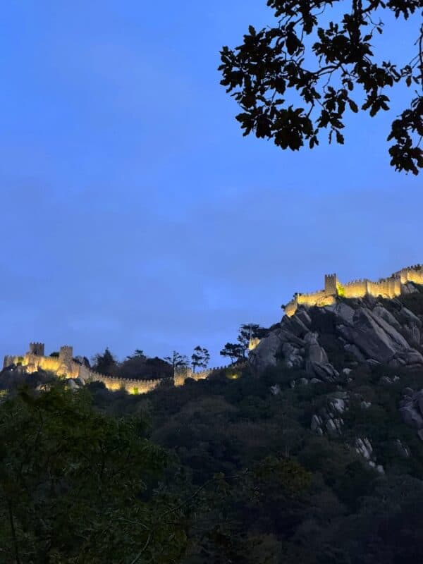 Night view of Sintra's castle walls illuminated on a hillside.