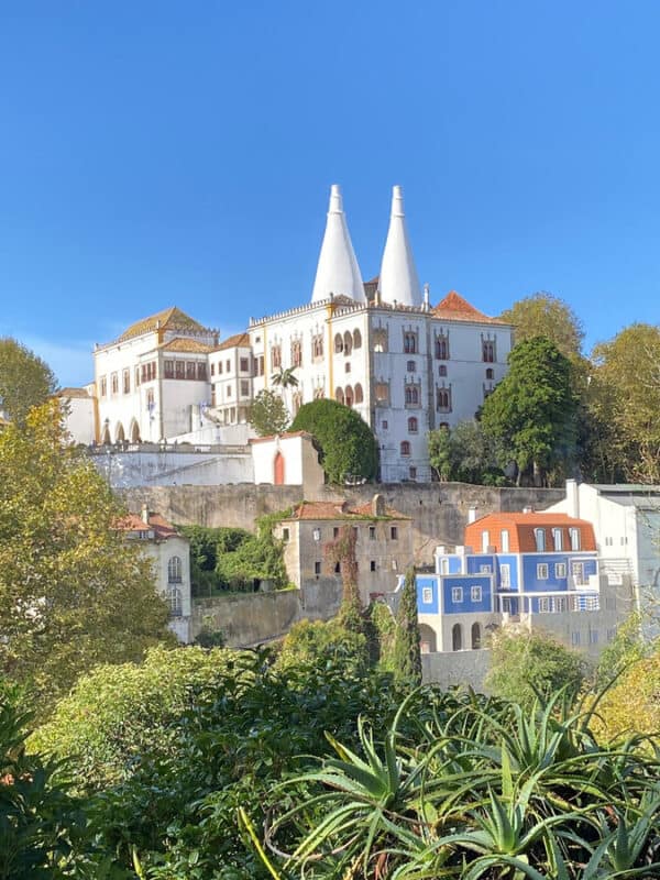 Colorful buildings and lush greenery in Sintra, Portugal with a castle in the background.