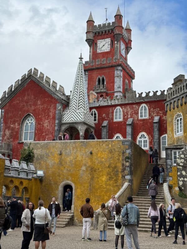 Colorful Pena Palace in Sintra Portugal with visitors exploring the grounds.