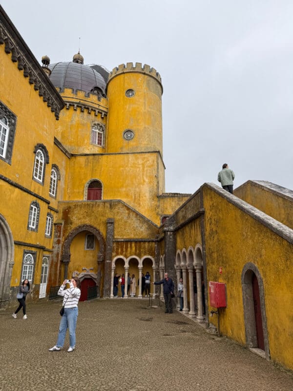 Colorful Pena Palace in Sintra, Portugal with visitors exploring the historic site.