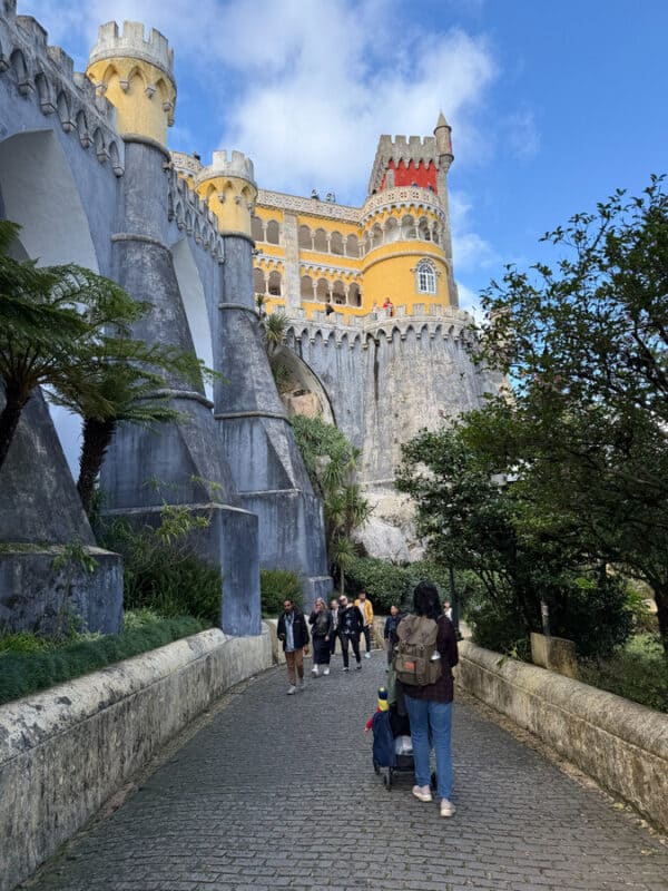 VacayWork author Sahana walking towards the colourful entrance of Pena Palace, surrounded by lush greenery.