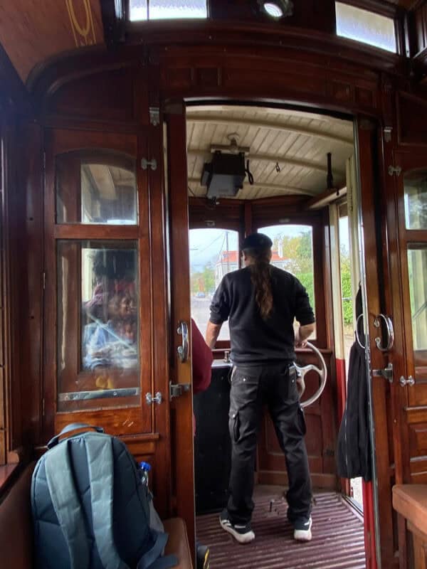 Tram driver operating the historic steering wheel inside the wooden Sintra tram