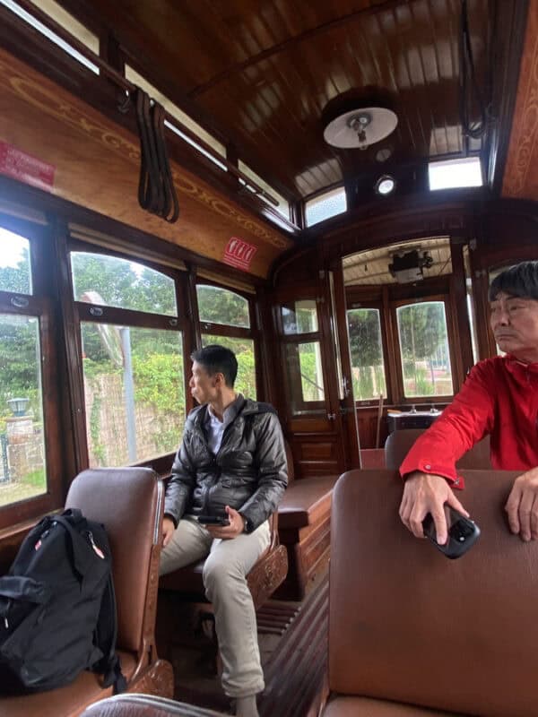 Vintage wooden interior of the historic Sintra tram with two tourists and plenty of empty seats