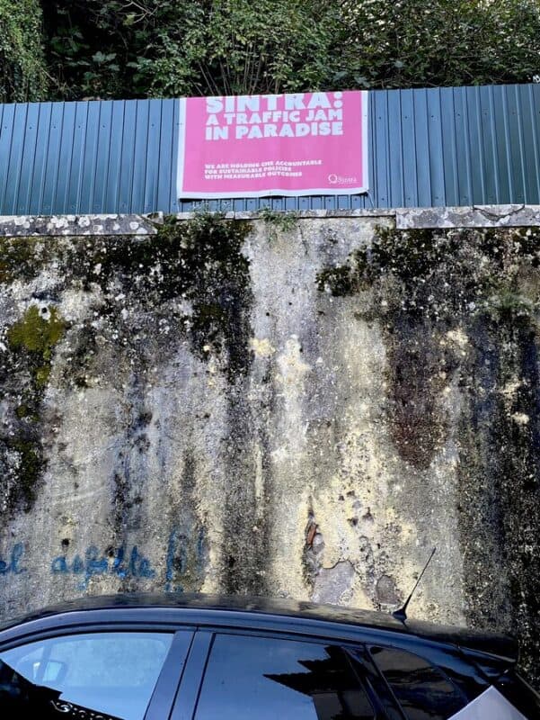 Local protest sign in Sintra reading, "Sintra, a traffic jam in paradise", displayed on a wall.
