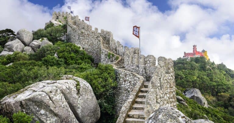 stone steps leading to moorish castle surrounded by greenery and pena palace seen in distance