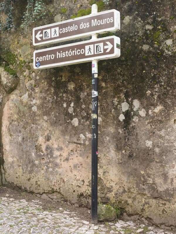 A sign points towards Castelo dos Mouros and the historic centre of Sintra from a cobbled path.